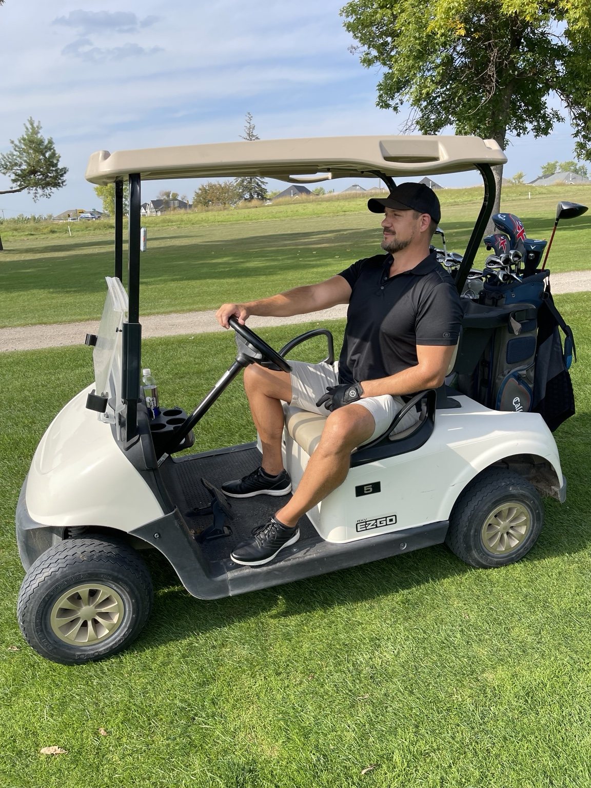 A regular golfer sitting in a golf cart on the course